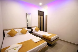 A hotel room with two beds, each with a wooden headboard, white bedding, and a single yellow pillow. - Hotel Golden Residency (Mumbai)
