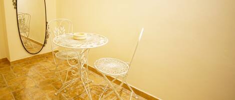 Un conjunto de mesa y silla de metal blanco frente a una pared amarilla, con un espejo grande en la pared.