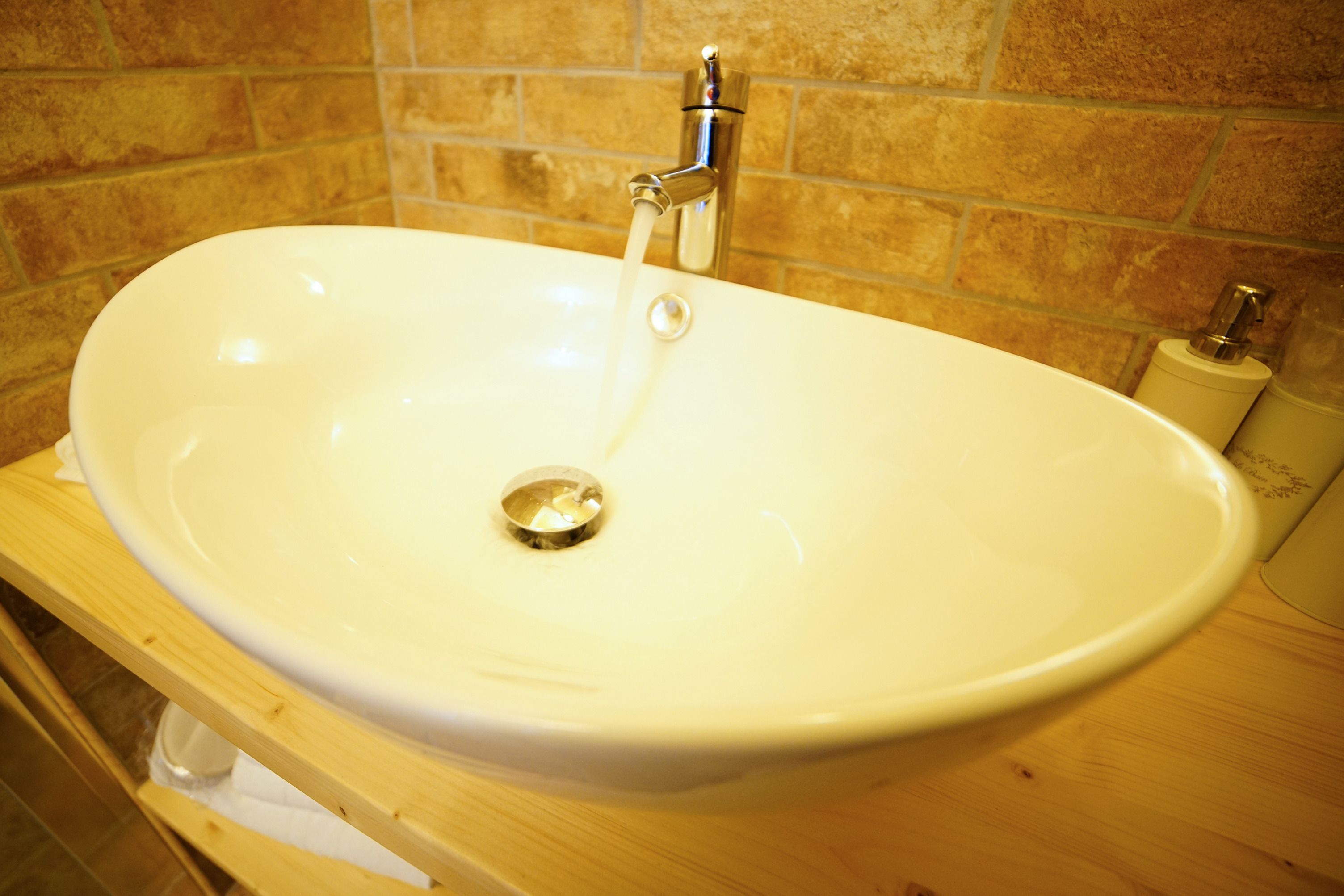 Un baño con un lavamanos blanco, una encimera de madera y una pared con azulejos.