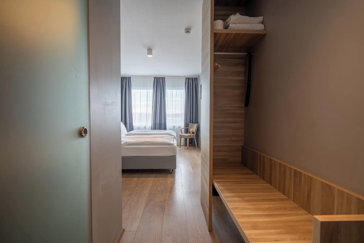 Une chambre d’hôtel moderne avec un plancher en bois, un lit, une chaise et un escalier en bois.