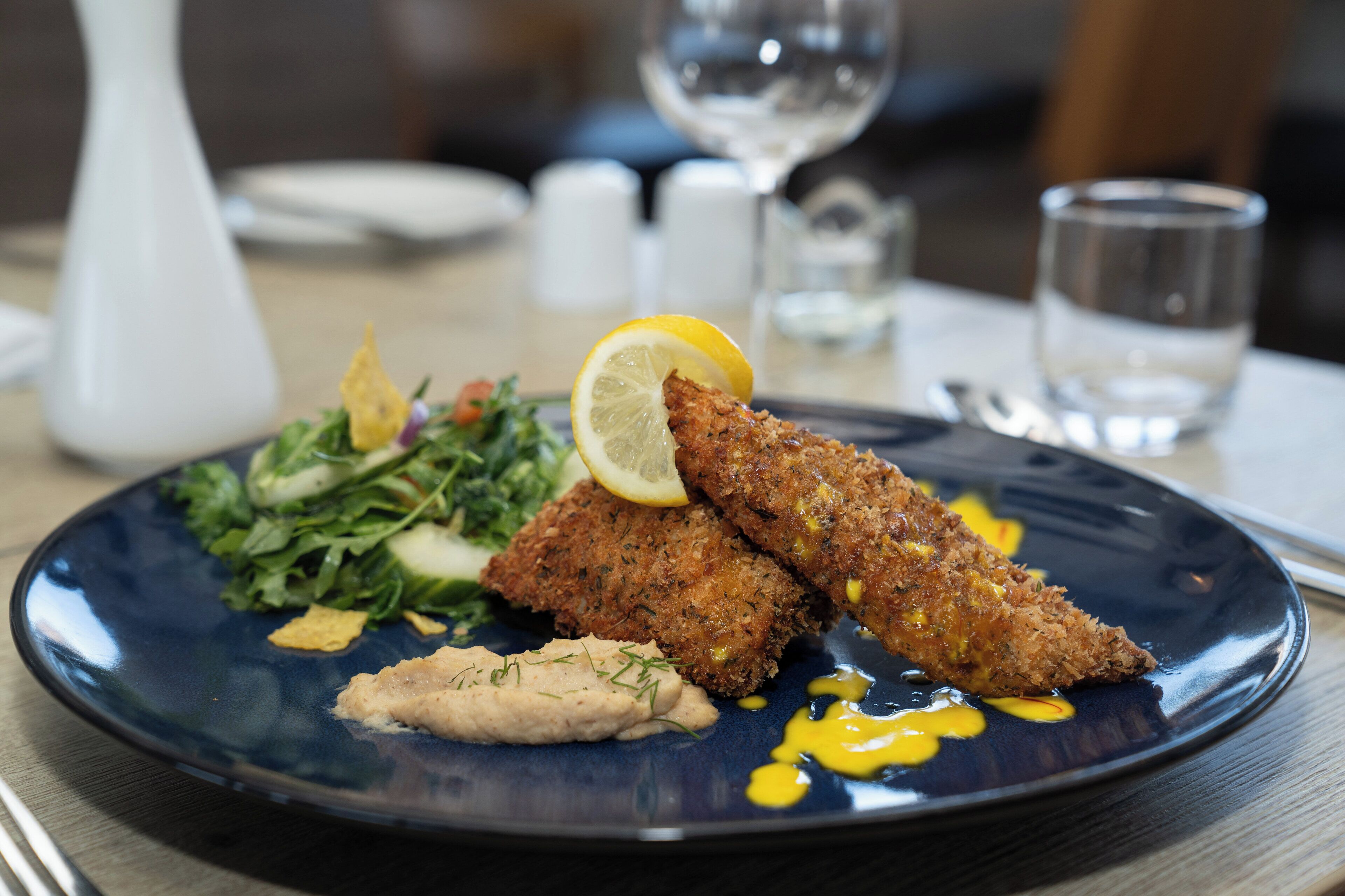 A plate of food with breaded cutlets, a lemon slice, and a side salad.