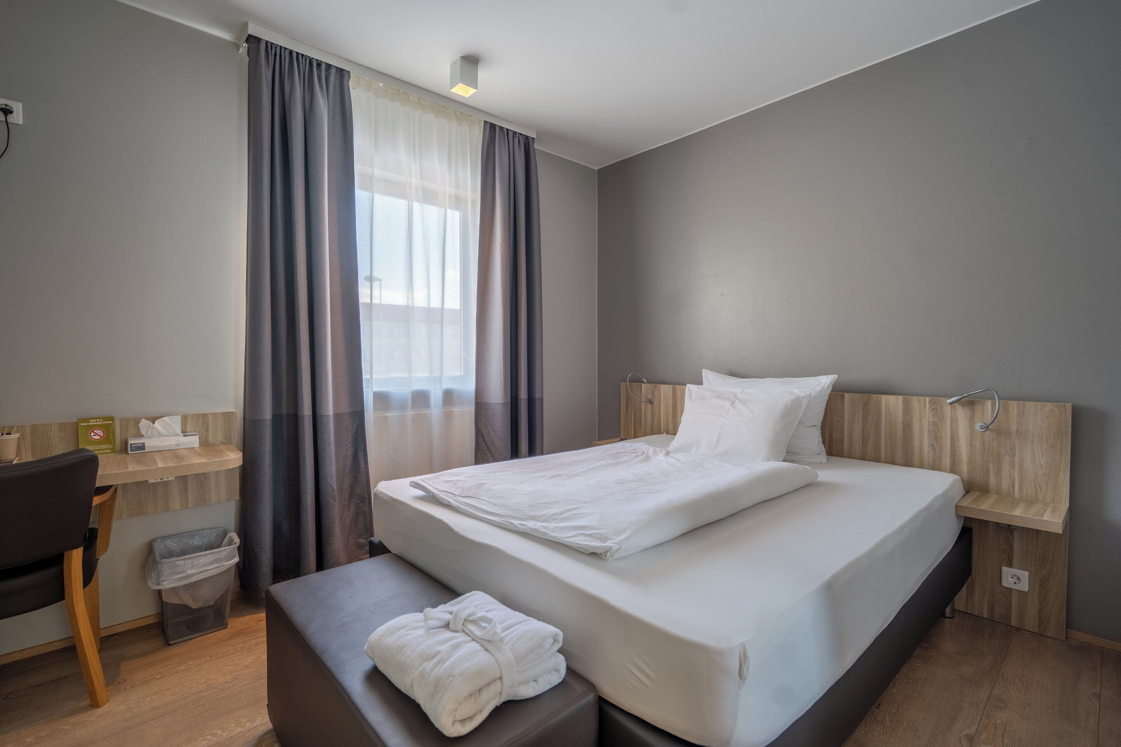 Una habitación de hotel moderna con una cama grande, un escritorio y una silla.