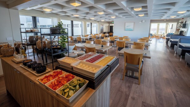 Un espace buffet proposant divers plats et une zone réservée aux repas, avec des tables et des chaises.