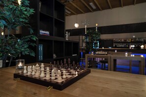 Un échiquier posé sur une table en bois, avec une bougie et une plante à proximité.