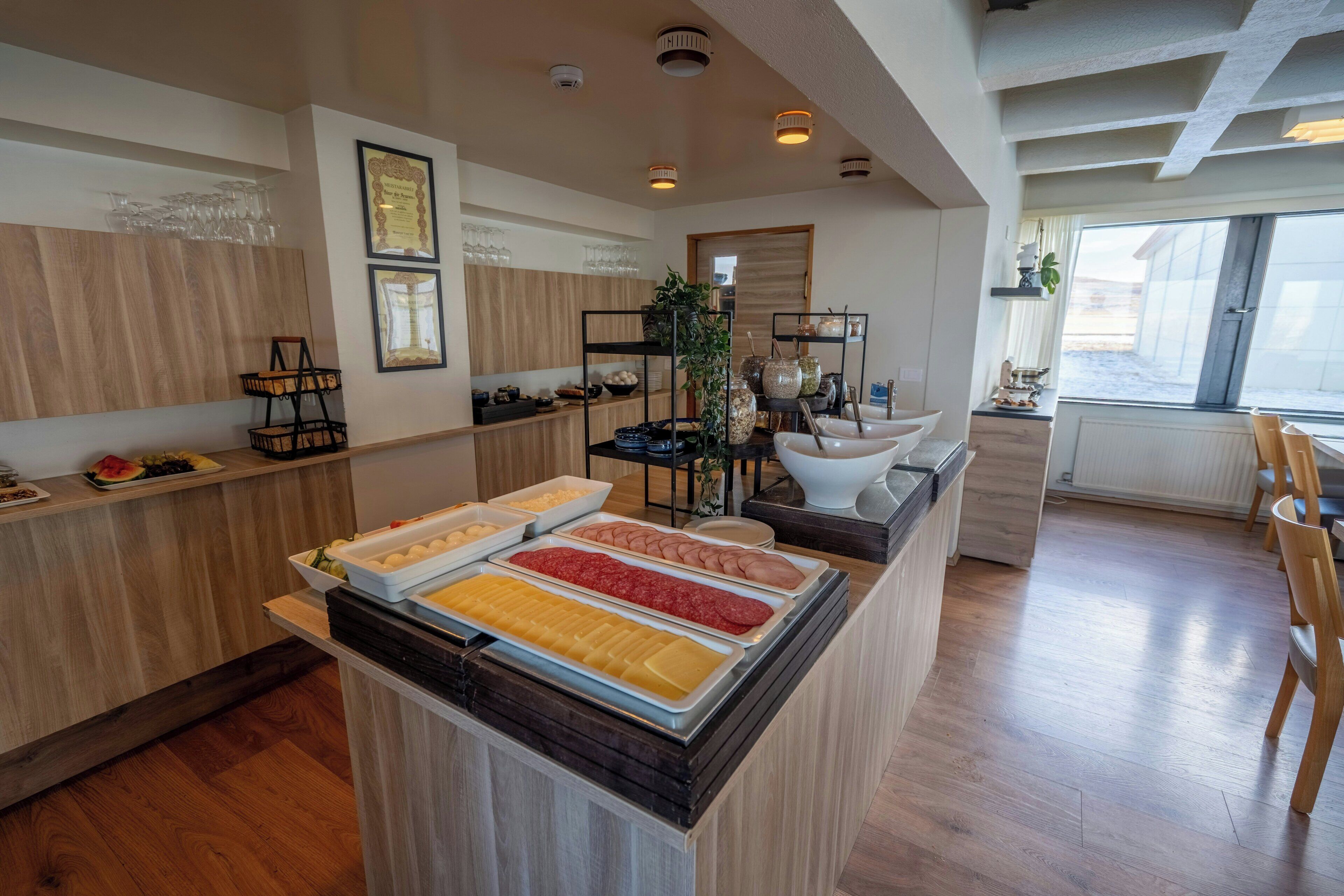 A buffet area with various food options, a wooden counter, and a window with a view.