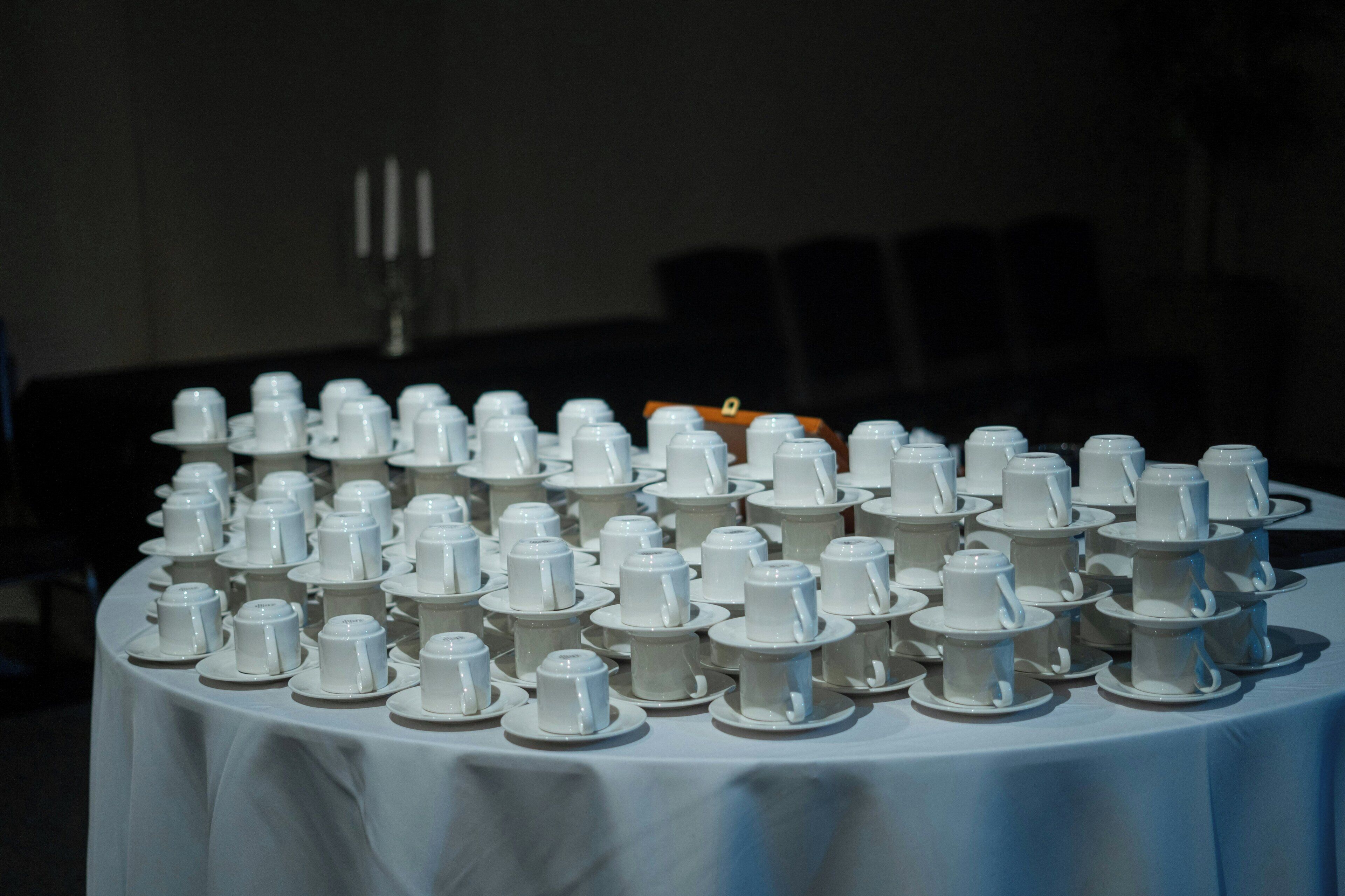Une table recouverte d’assiettes et de tasses blanches, disposées en rangées.
