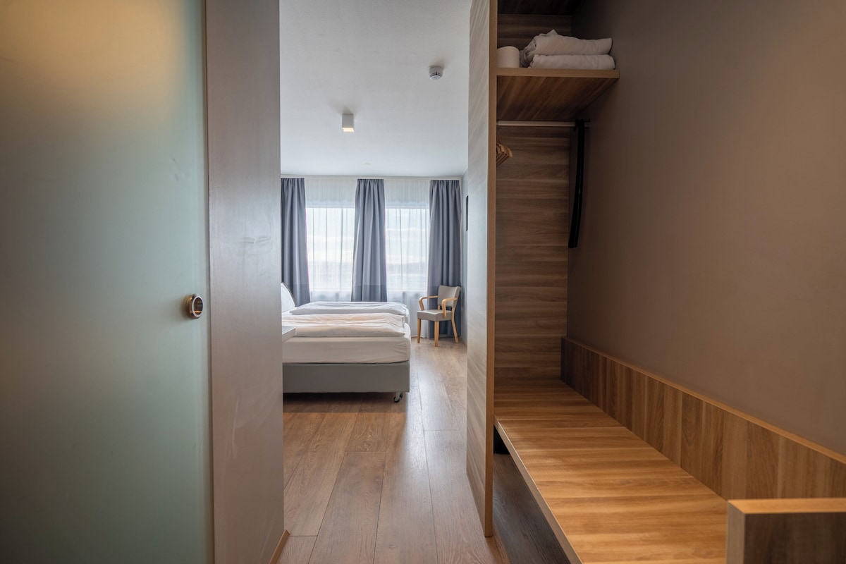 Une chambre d’hôtel moderne avec un plancher en bois, un lit, une chaise et un escalier en bois.