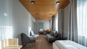 Une chambre d’hôtel moderne avec un plafond en bois, un lit, un canapé, une chaise et un bureau.