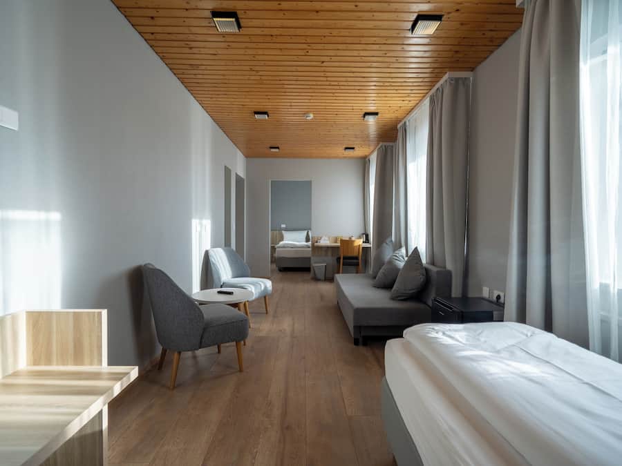 Une chambre d’hôtel moderne avec un plafond en bois, un lit, un canapé, une chaise et un bureau.