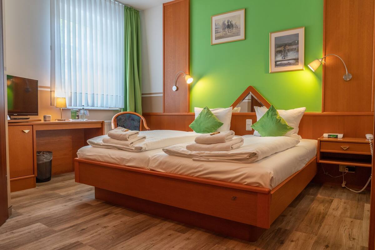 A hotel room with a bed, desk, chair, and a television.