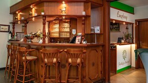 A bar area with wooden chairs, a counter with various items, and a sign reading "Emptang". - Parkhotel Neustadt (Neustadt)