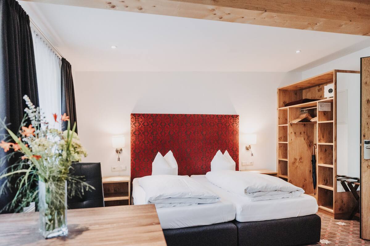Une chambre d’hôtel avec un lit, une armoire en bois et une table de chevet avec une lampe.