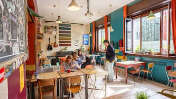 Un café con mesas, sillas y una persona de pie.