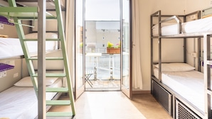 Un dormitorio con literas, una escalera, una mesita con una planta y vistas a través de una puerta de cristal.