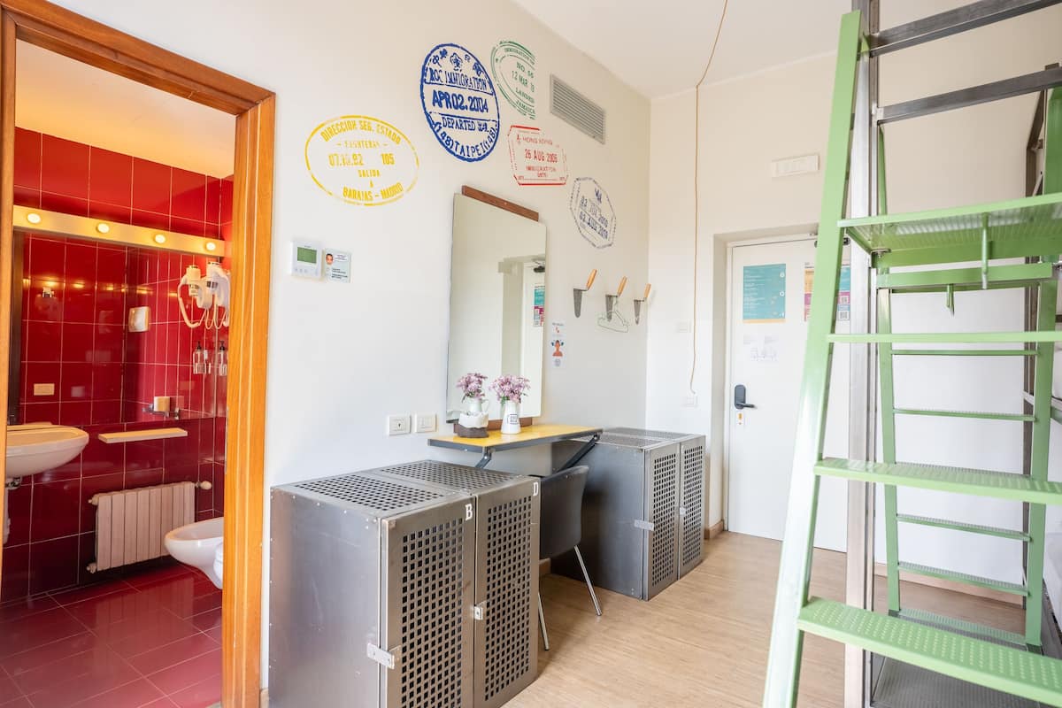 A hotel room with a red-tiled bathroom, a desk with a mirror, and a green metal ladder.