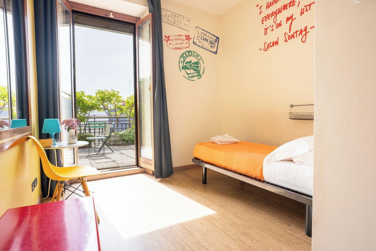 Habitación de hotel con cama, escritorio, silla y vista al exterior.
