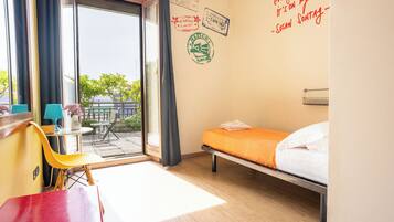 Habitación de hotel con cama, escritorio, silla y vista al exterior.