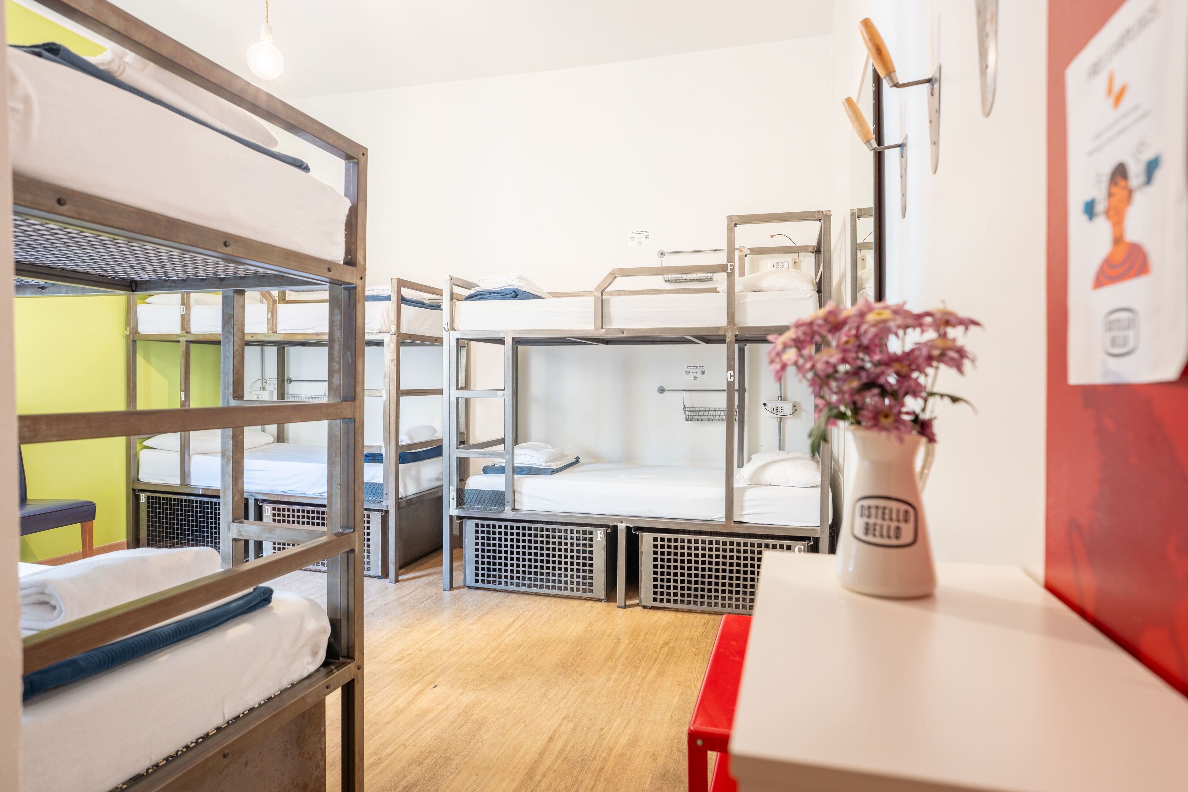 Een slaapkamer met een stapelbed, een kleine tafel en een bloevas.