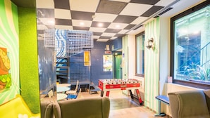 Una habitación con mesa de fútbol, una escalera y un ventanal con vistas a plantas.
