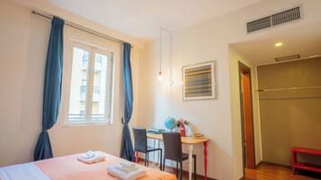 Een hotelkamer met een bed, een bureau met een computer, een stoel, een wereldbol en een raam met gordijnen.