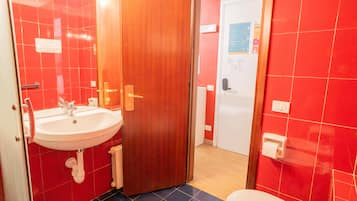 A bathroom with a sink, toilet, and a wooden door.