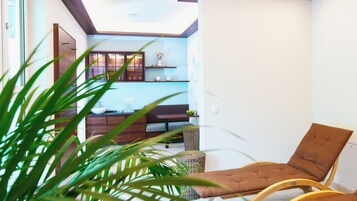 Una sala moderna con un banco de madera, una mesa de centro de vidrio y una estantería empotrada con objetos decorativos.