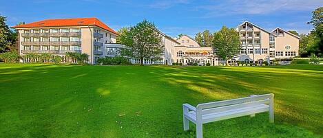 A hotel with multiple buildings, a grassy lawn, and a white bench.