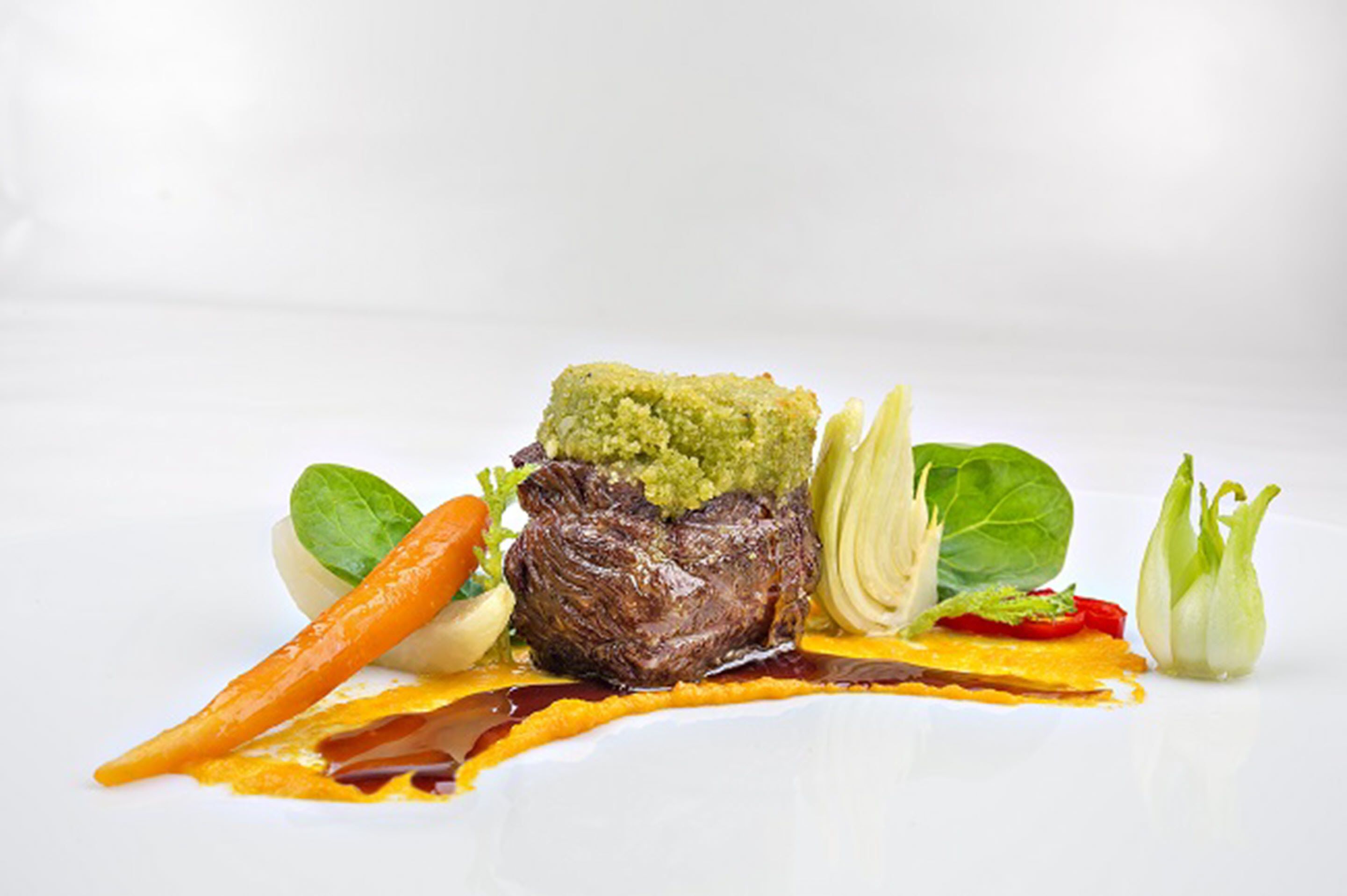 Un plato con carne, verduras de hoja y vegetales.