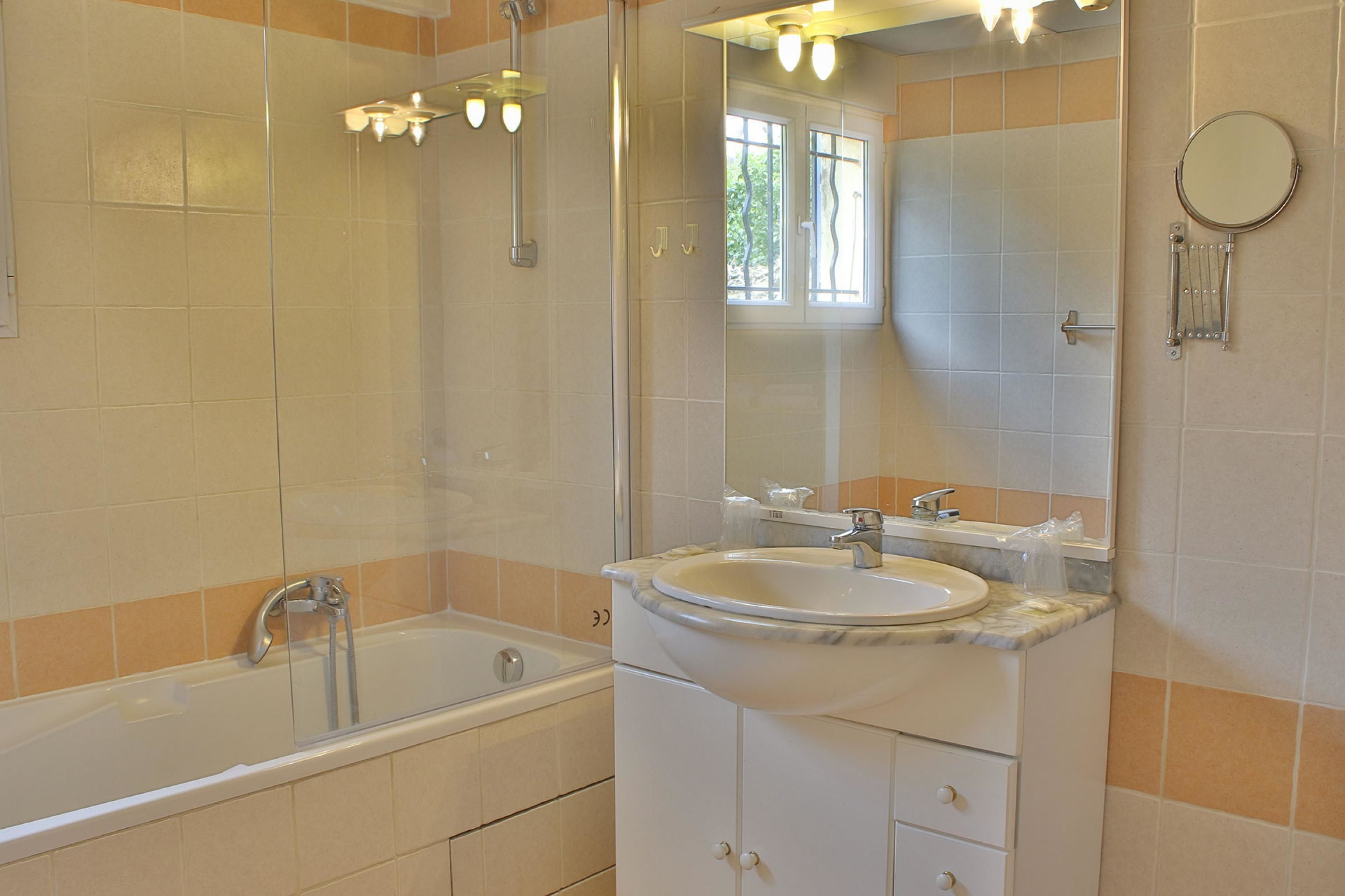 A bathroom with a bathtub, a sink, and a mirror.