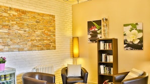 A living room with a brick wall, a bookshelf, and leather chairs.