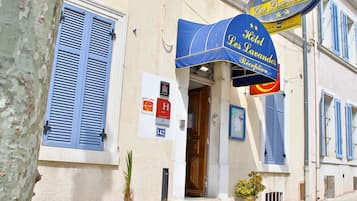 L’entrée d’un hôtel, avec un auvent bleu, une porte en bois et une enseigne.