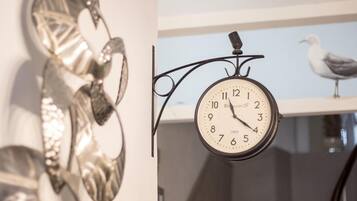 A wall-mounted clock with a bird on a shelf in the background.
