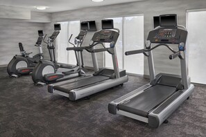Un gimnasio con cintas de correr, elípticas y una bicicleta estática.