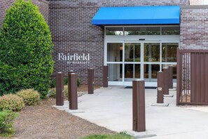 Un edificio de ladrillo con un toldo azul y un letrero que dice "Fairfield BY MARRIOTT".