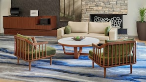Un salon moderne avec une cheminée en pierre, un canapé, deux fauteuils et une table basse.