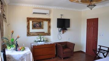 Una habitación con un aparador de madera, un sillón marrón, un televisor montado en la pared y una puerta roja.