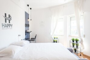Una habitación de hotel luminosa con cama, escritorio y ventana con cortinas.