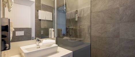 A modern bathroom with a glass-enclosed shower, a white sink, and a large mirror.