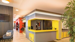 A hotel reception area with a modern design, featuring a reception desk, seating area, and a staircase leading to other rooms. - Hwest Hotel Hall (Hall In Tirol)