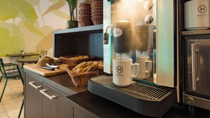 A coffee machine with a digital display, baskets of bread, and a potted plant in a hotel setting. - Hwest Hotel Hall (Hall In Tirol)