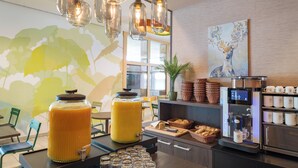 A breakfast bar with juice dispensers, baskets of bread, and a coffee machine. - Hwest Hotel Hall (Hall In Tirol)