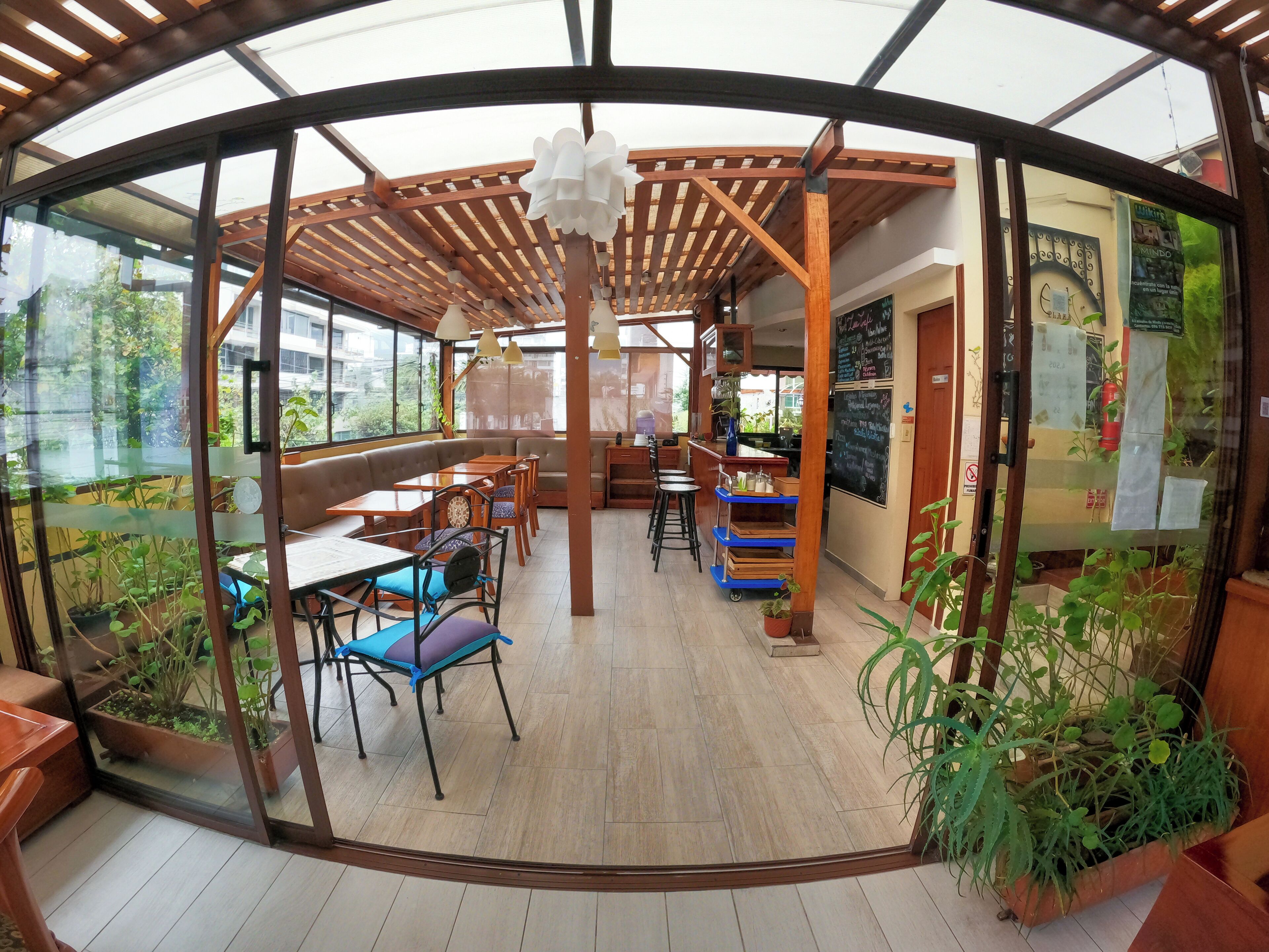 A restaurant with a wooden pergola, seating area, and a chalkboard menu.