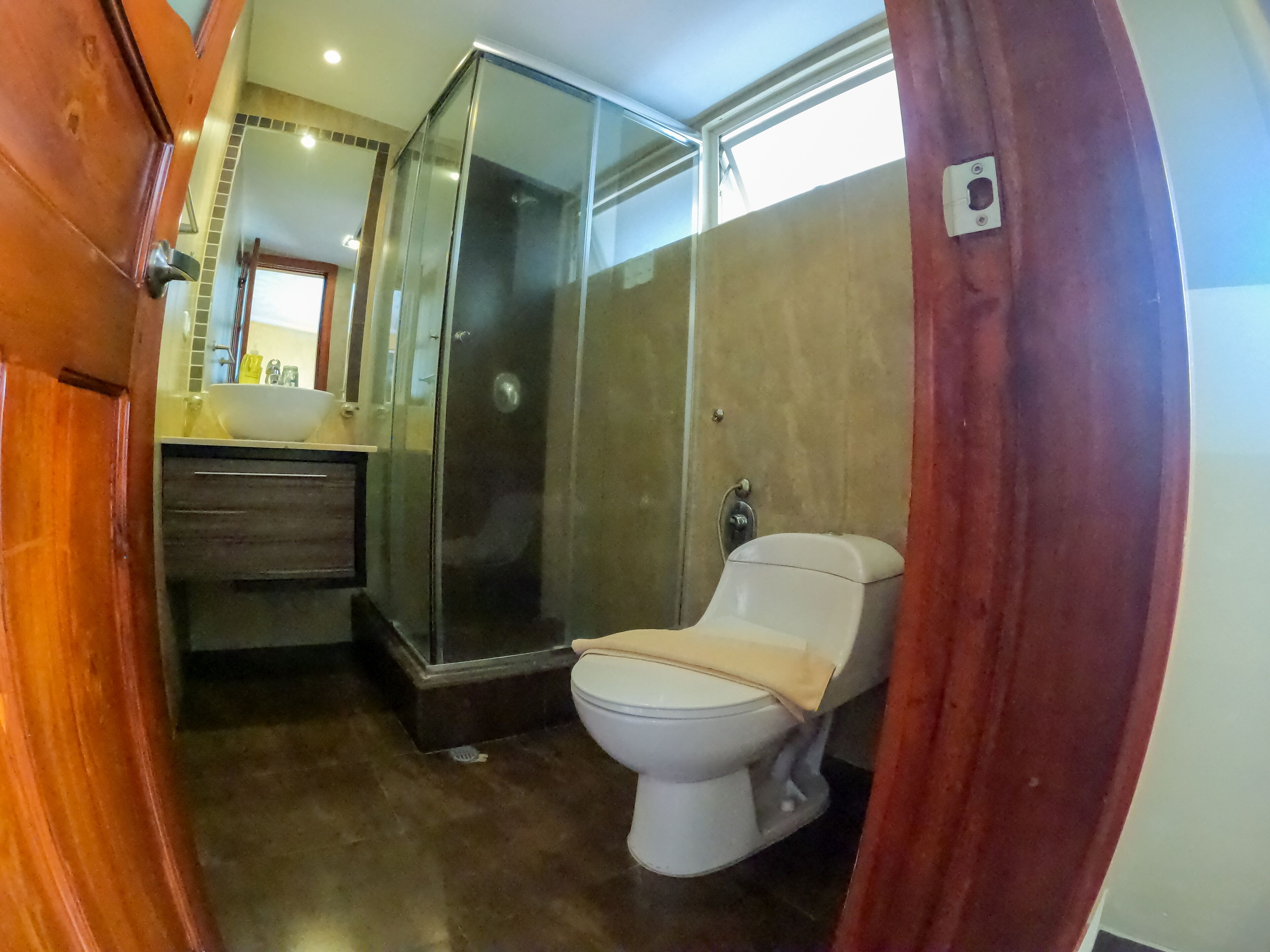 Un baño compacto con inodoro, cabina de ducha de vidrio y lavamanos.