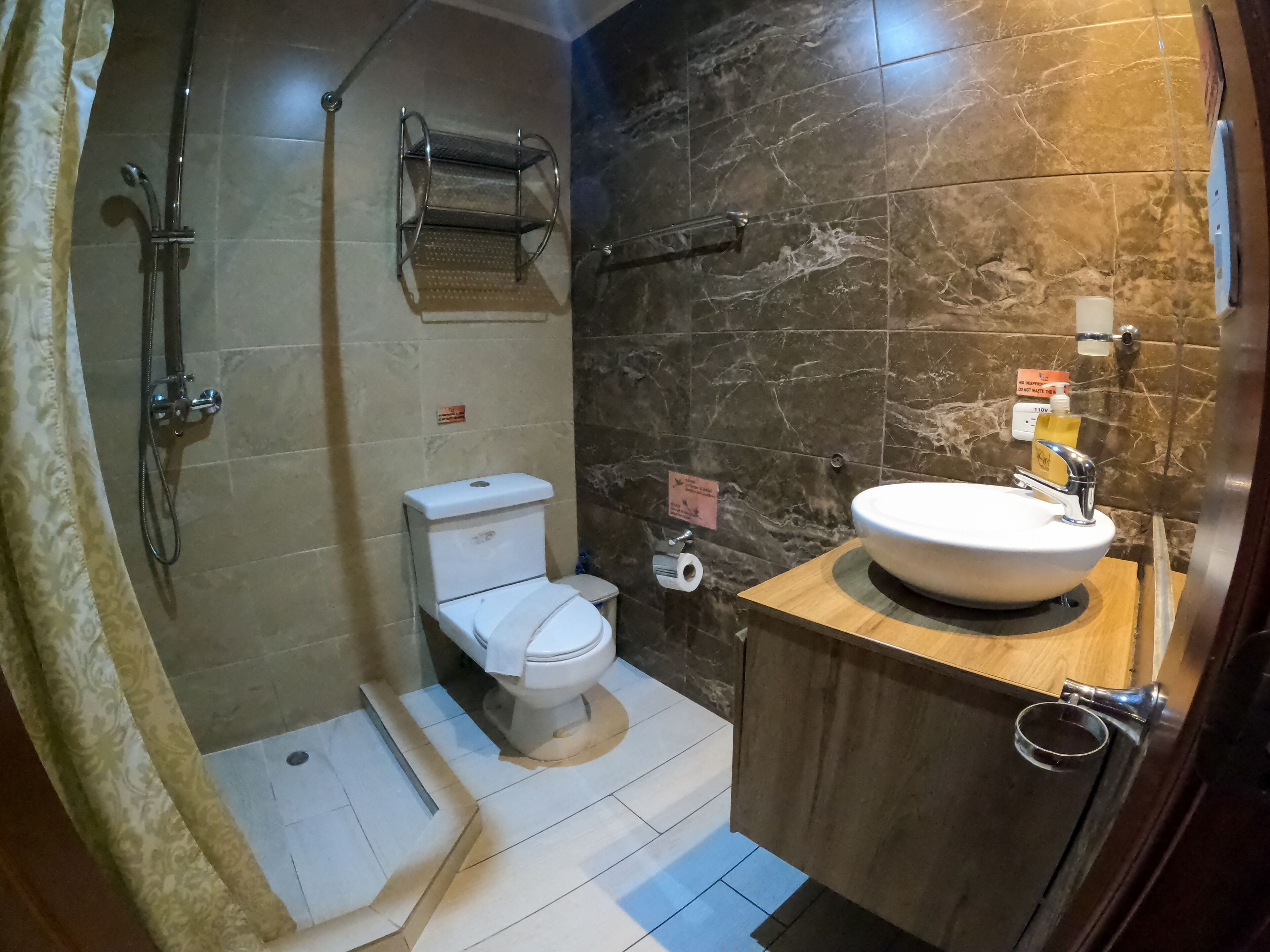 A bathroom with a toilet, sink, shower, and towel rack.