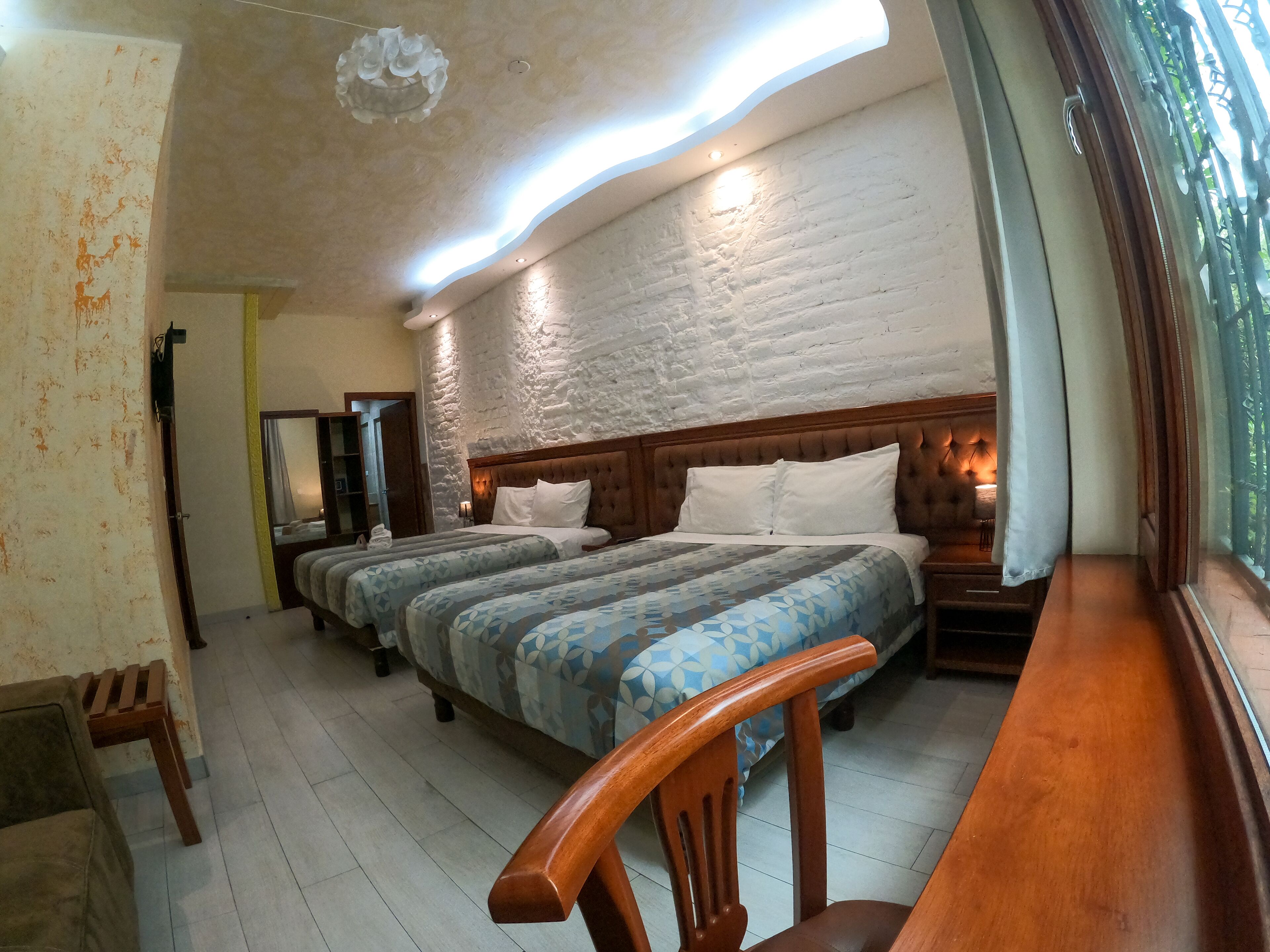 A hotel room with a large bed, a wooden chair, a nightstand, and a mirror.