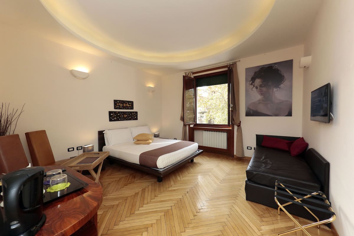 Een moderne slaapkamer met een bed, een bank, een bureau en een raam.