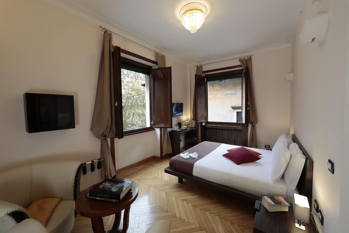 Een hotelkamer met een bed, een bureau, een stoel, een televisie en een raam met gordijnen.