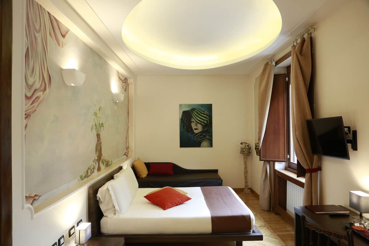 Een hotelkamer met een bed, een bureau, een televisie en een schilderij aan de muur.
