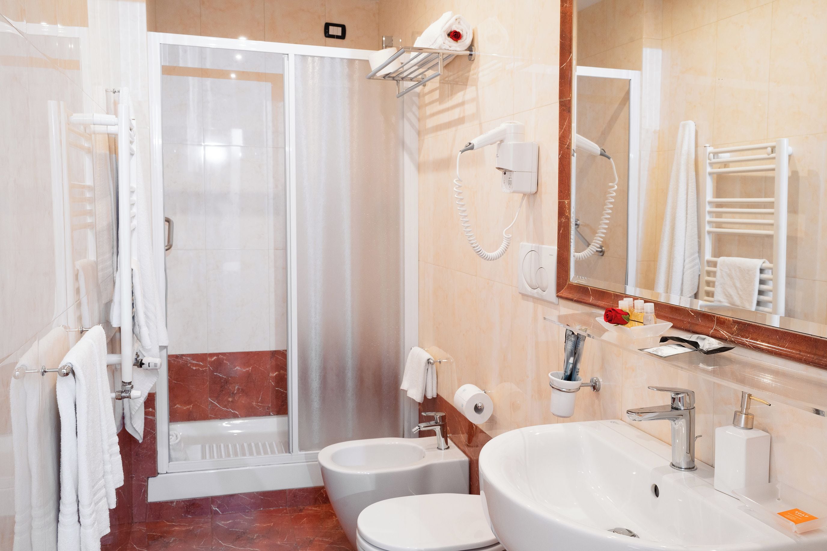Ein modernes Badezimmer mit begehbarer Dusche, zwei Toiletten, einem Waschbecken und einem Spiegel.