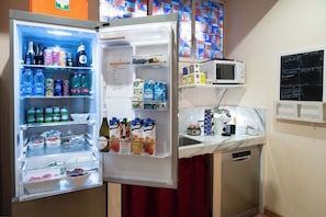 A compact kitchen with a refrigerator, microwave, and a chalkboard menu. - Residenza delle Arti (Rome)